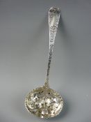 AN ORNATE SILVER SUGAR SIFTER, the bowl with raised fruit and leaf decoration and the handle with