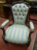 A VICTORIAN CARVED WALNUT BUTTON BACKED SALON ARMCHAIR, upholstered in a classical Regency stripe,