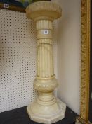 A CARVED ALABASTER CIRCULAR TOPPED STAND, the 23 cms diameter top with inverted leaf carving on a