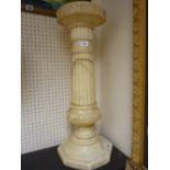 A CARVED ALABASTER CIRCULAR TOPPED STAND, the 23 cms diameter top with inverted leaf carving on a