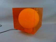 A RETRO TABLE LAMP circa 1960, orange perspex with white globular glass interior, 30.5 cms high with