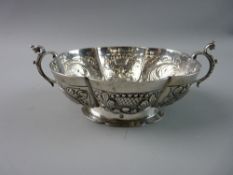 AN OVAL CONTINENTAL SILVER TWIN HANDLED BOWL, segmented panels to the exterior with leaves and