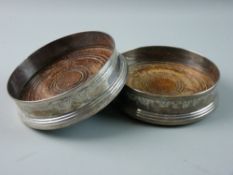 A PAIR OF WOODEN BASED CIRCULAR SILVER WINE COASTERS with garland decoration in the classical style,