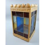 A SQUARE COLOURED GLASS METAL FRAMED HANGING LANTERN, each side having eleven coloured and leaded