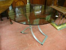 A MID CENTURY CHROMED STEEL GLASS TOPPED TABLE, the 91.5 cms diameter 10 mm thick top on a shaped