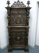 A CARVED RENAISSANCE STYLE CONTINENTAL CUPBOARD having a drop down top section over a central frieze