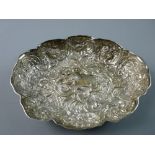 AN OVAL SILVER DISH with all over raised decoration, scrolls, animals, fruit and angelic masks