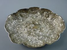 AN OVAL SILVER DISH with all over raised decoration, scrolls, animals, fruit and angelic masks