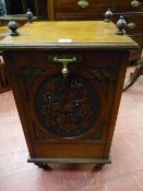 AN EDWARDIAN MAHOGANY CARVED FRONT COAL BOX with brass carry handles and fittings on turned feet