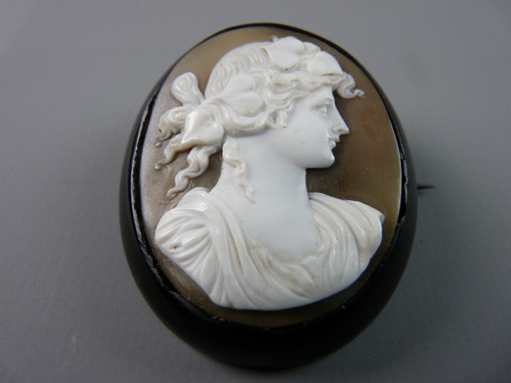 AN ANTIQUE OVAL WHITBY JET FRAMED AND BACKED CAMEO BROOCH with Victorian young lady bust having