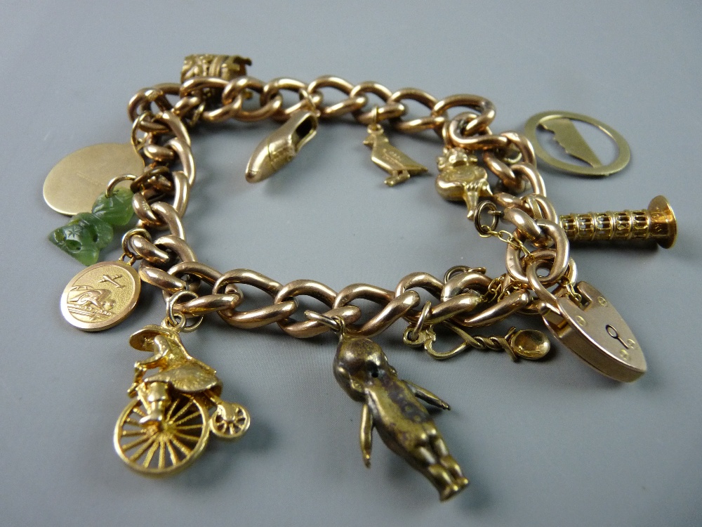 A NINE CARAT GOLD CHARM BRACELET with approximately ten charms, padlock and safety chain, 27 grms