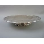 A CIRCULAR SILVER PLAIN TAZZA with lined border on a short decorated pedestal and with