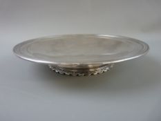 A CIRCULAR SILVER PLAIN TAZZA with lined border on a short decorated pedestal and with