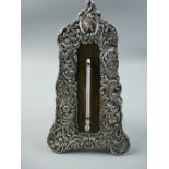 A SILVER EASEL THERMOMETER STAND with raised all over floral decoration and the thermometer set into