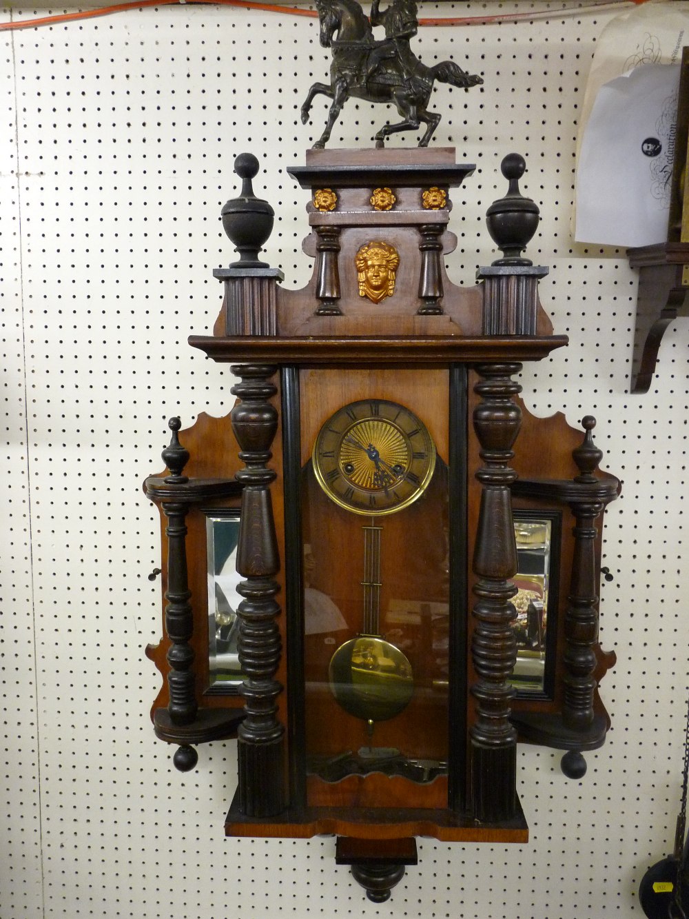 AN UNUSUAL VIENNA TYPE WALL CLOCK, pendulum driven brass faced movement in a walnut and mixed wood