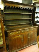 A MID 18th CENTURY WELSH OAK DRESSER, the three shelf wide boarded rack with inverted cornice over a