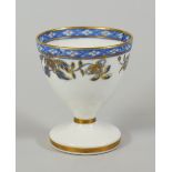 A RARE SWANSEA PORCELAIN EGG CUP decorated with a continuous band of blue and gilded flowers and