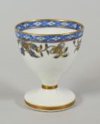 A RARE SWANSEA PORCELAIN EGG CUP decorated with a continuous band of blue and gilded flowers and