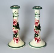 A PAIR OF LLANELLY CANDLESTICK HOLDERS with circular bases and decorated with tea-roses,