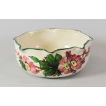 LLANELLY POTTERY BOWL painted with wild-roses and having a crimped rim, stencilled mark to base,