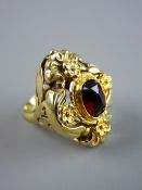 A LARGE OVAL FOURTEEN CARAT GOLD FLORAL DRESS RING with centre oval garnet set, possibly into an