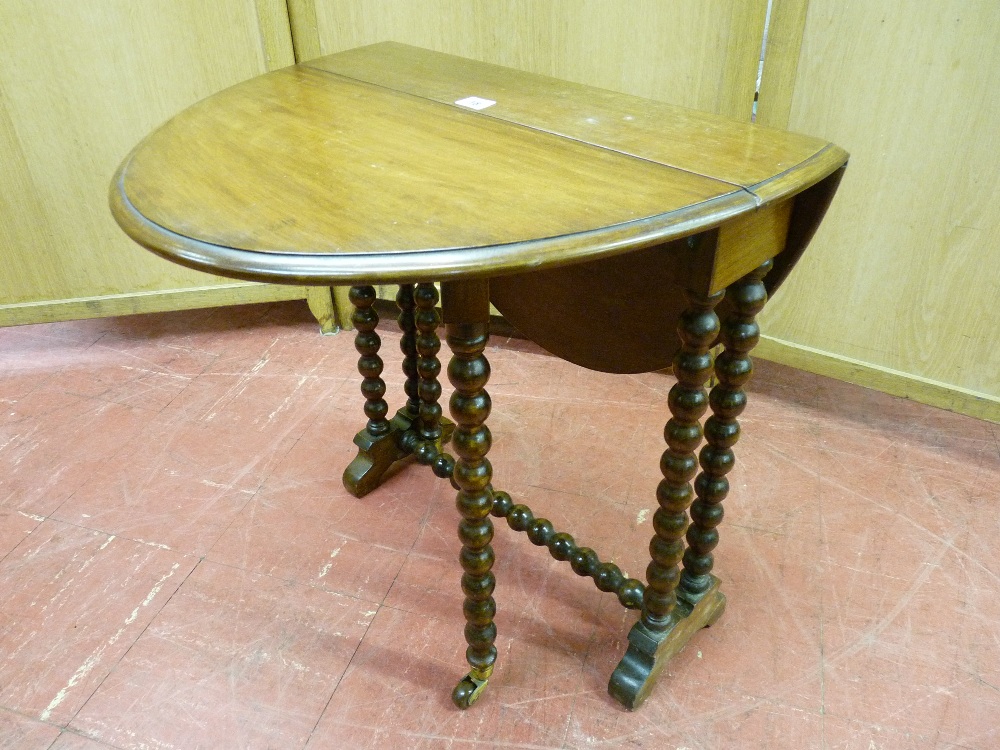 AN EDWARDIAN MAHOGANY OVAL DROP LEAF SUTHERLAND TEA TABLE, with bobbin supports and castors