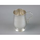 A SMALL HAMMERED SILVER TANKARD with scrollwork handle on a stepped circular base, 8 cms high,