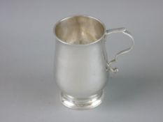 A SMALL HAMMERED SILVER TANKARD with scrollwork handle on a stepped circular base, 8 cms high,