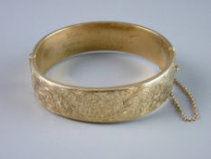 A NINE CARAT GOLD HOLLOW BANGLE, half bright cut with floral decoration and with presentation