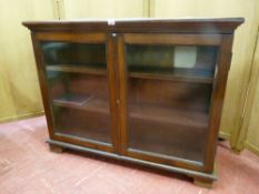 A LOW TWO DOOR BOOKCASE with twin glass doors and fixed interior shelves on bracket corner feet,