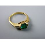 AN EIGHTEEN CARAT GOLD DRESS RING with centre square cut emerald and flanking baguette diamonds,