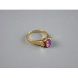 AN INDIAN GOLD DRESS RING having an oval centre ruby on a majestic scrolled basket, size 'N', 3 grms