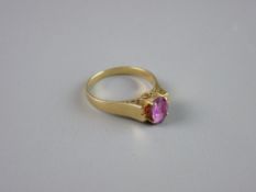 AN INDIAN GOLD DRESS RING having an oval centre ruby on a majestic scrolled basket, size 'N', 3 grms