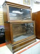 A GLOBE WERNICKE POLISHED OAK TWO PIECE BOOKCASE with wide plain glass doors and each section with