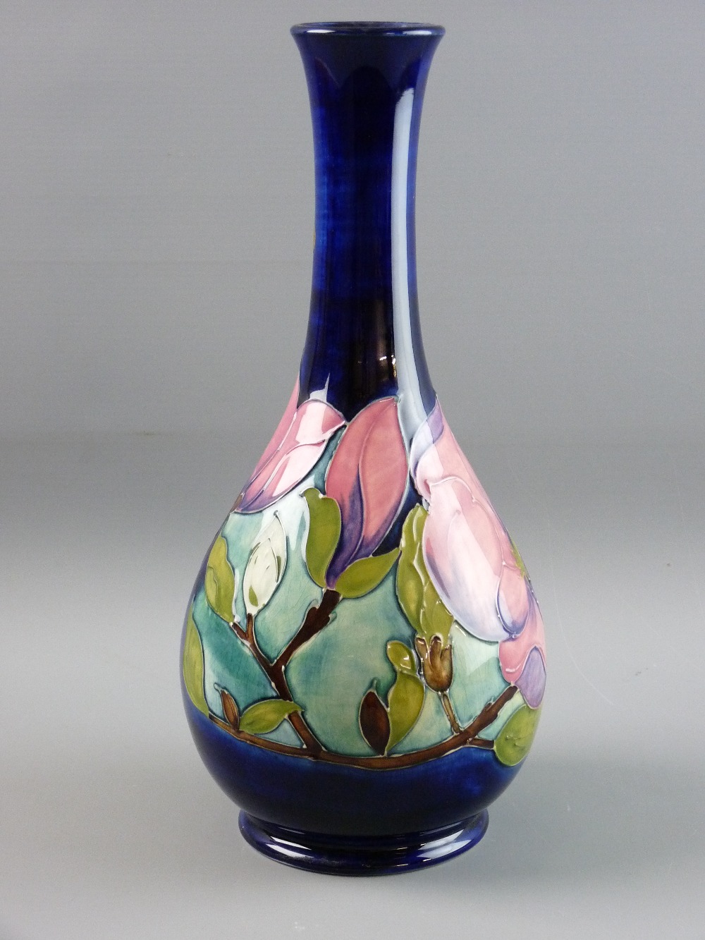 A MOORCROFT 'MAGNOLIA' BOTTLE VASE, 32 cms high, decorated on a cobalt blue ground, original