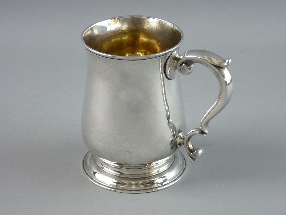 A GEORGE II SILVER TANKARD of plain waisted form with scroll handle and circular foot, 12 cms