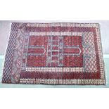 AN EASTERN RED GROUND WOOLLEN RUG with Greek Key border, multi-panelled centre and open bordered