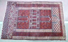 AN EASTERN RED GROUND WOOLLEN RUG with Greek Key border, multi-panelled centre and open bordered