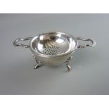 A CIRCULAR SILVER STRAINER & BOWL, the bowl on three shell and web supports and the strainer with