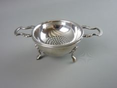 A CIRCULAR SILVER STRAINER & BOWL, the bowl on three shell and web supports and the strainer with