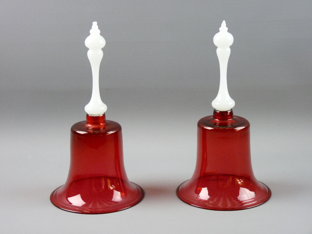 A PAIR OF CRANBERRY GLASS HAND BELLS, 27 cms high (no clangers)