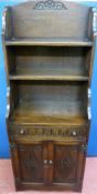 A REPRODUCTION OAK BOOKCASE CUPBOARD, the waterfall top with central carving and fixed shelves above