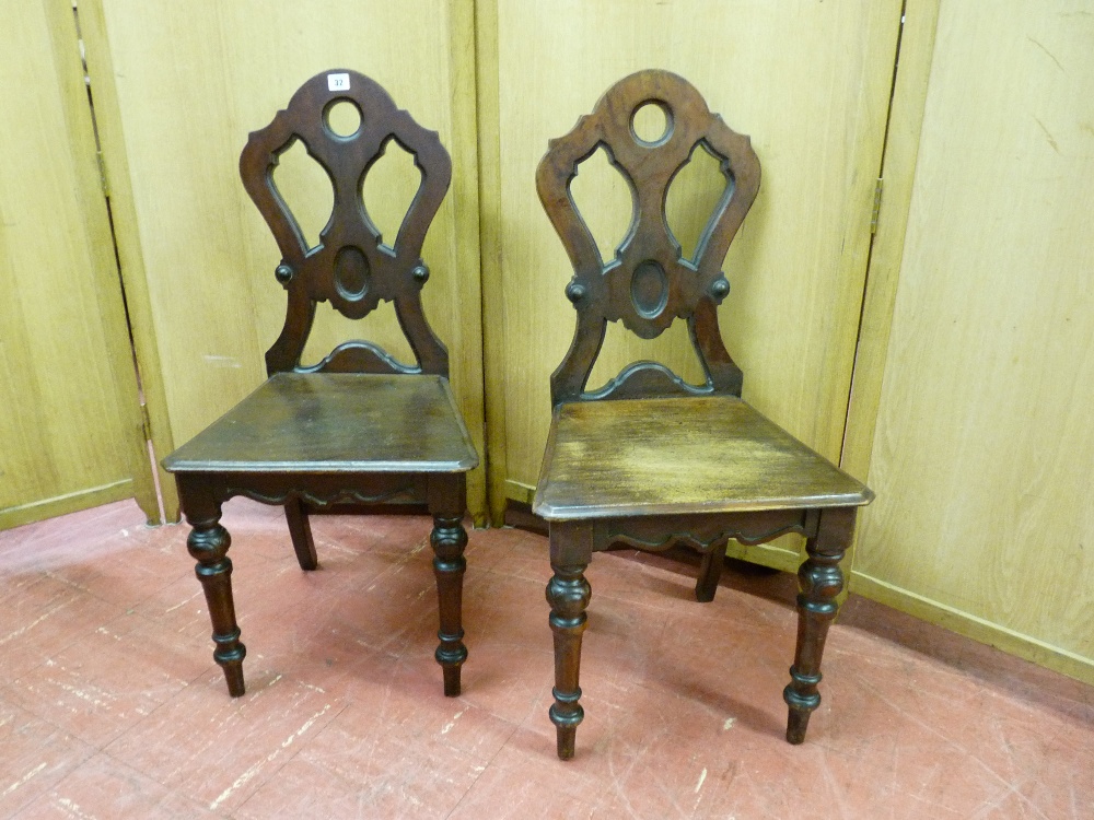 A PAIR OF LATE EDWARDIAN MAHOGANY HALL CHAIRS with Gothic style shaped and pierced backs and