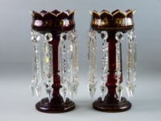 A PAIR OF VICTORIAN RUBY GLASS LUSTRES having crown patterned tops with gilded decoration and