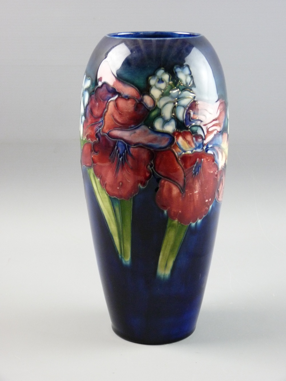 A MOORCROFT 'ORCHID & SPRING FLOWERS' VASE, 26 cms high, decorated on a cobalt blue ground,