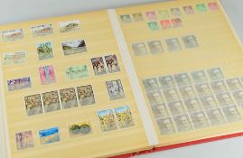 A RED HARDBACK ALBUM containing a mixture of mainly Spanish stamps