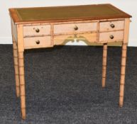 A PINE BAMBOO EFFECT KNEEHOLE DESK having a tooled green leather top and a bank of five drawers