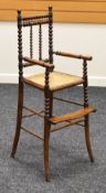 A LATE NINETEENTH CENTURY MAHOGANY CHILD'S HIGH-CHAIR having a footrest and bobbin supports and with