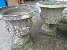 A PAIR OF SANDSTONE GARDEN URNS on square bases with leaf form bodies