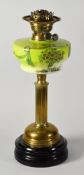 AN ANTIQUE OIL LAMP having a painted green glass reservoir supported by a reeded brass column with